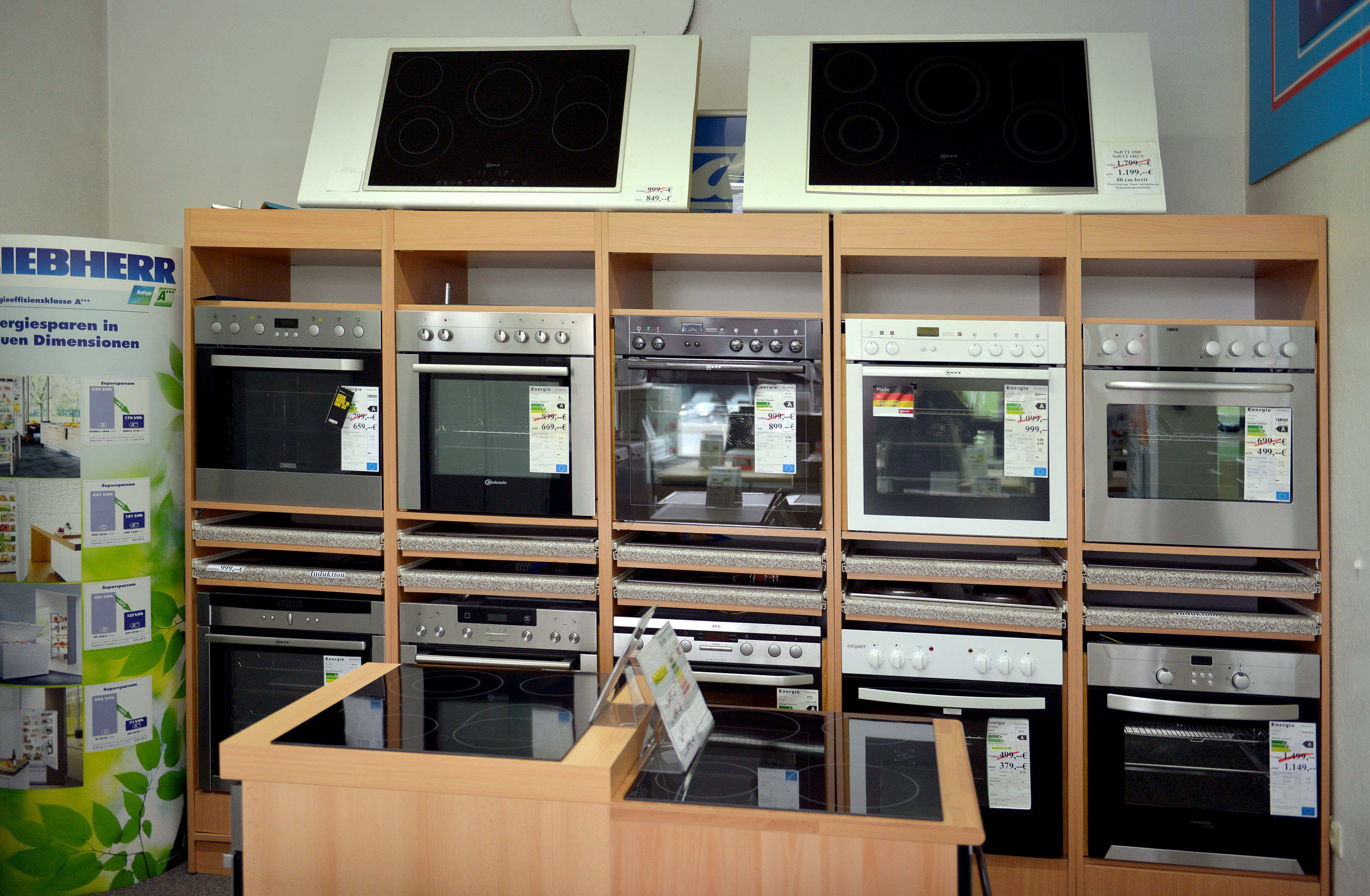 Reihe moderner Einbauküchengeräte, darunter Backöfen und Kochfelder in einem Geschäft.