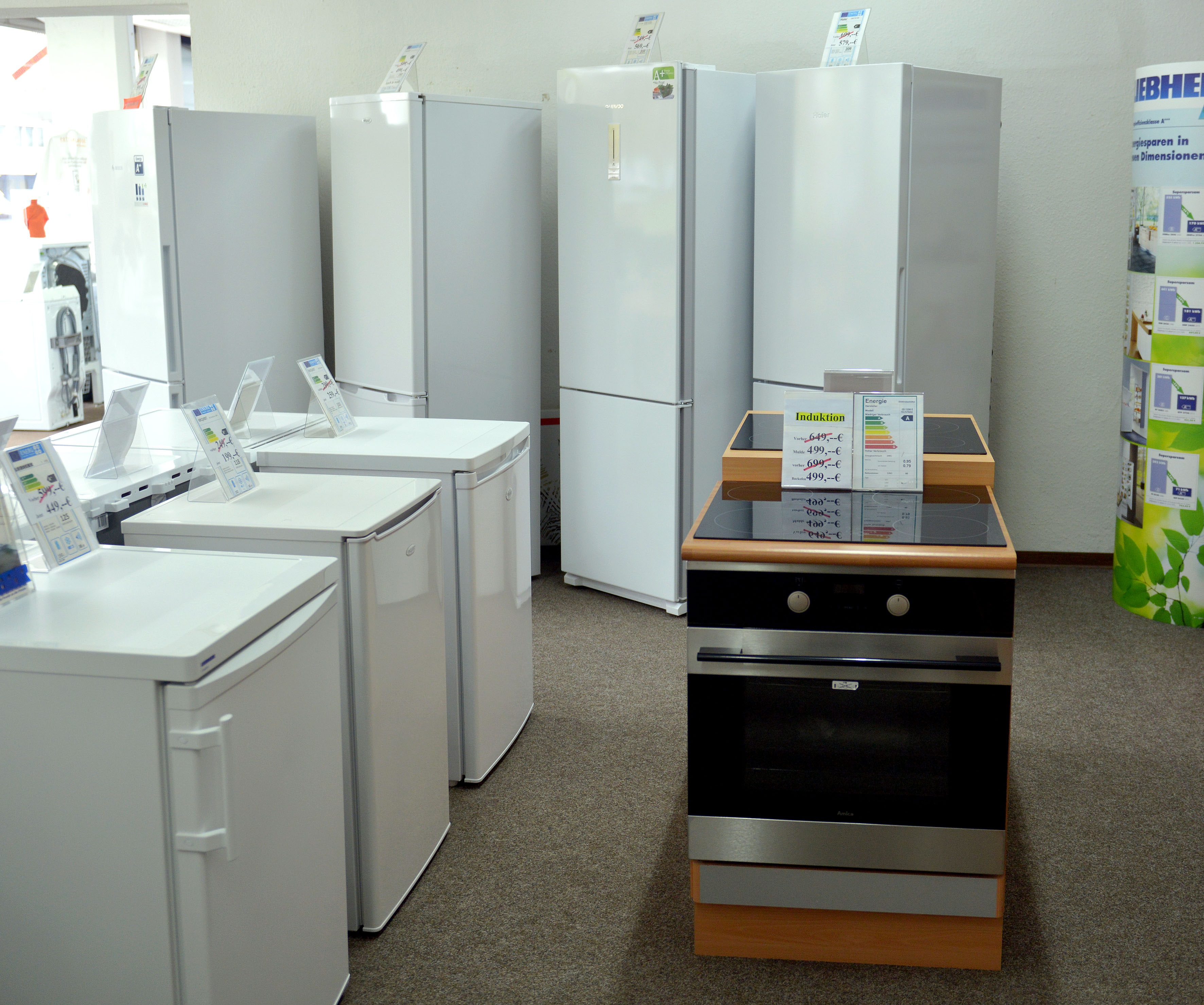 Elektrogeräte in einem Geschäft, darunter Kühlschränke und ein Herd.