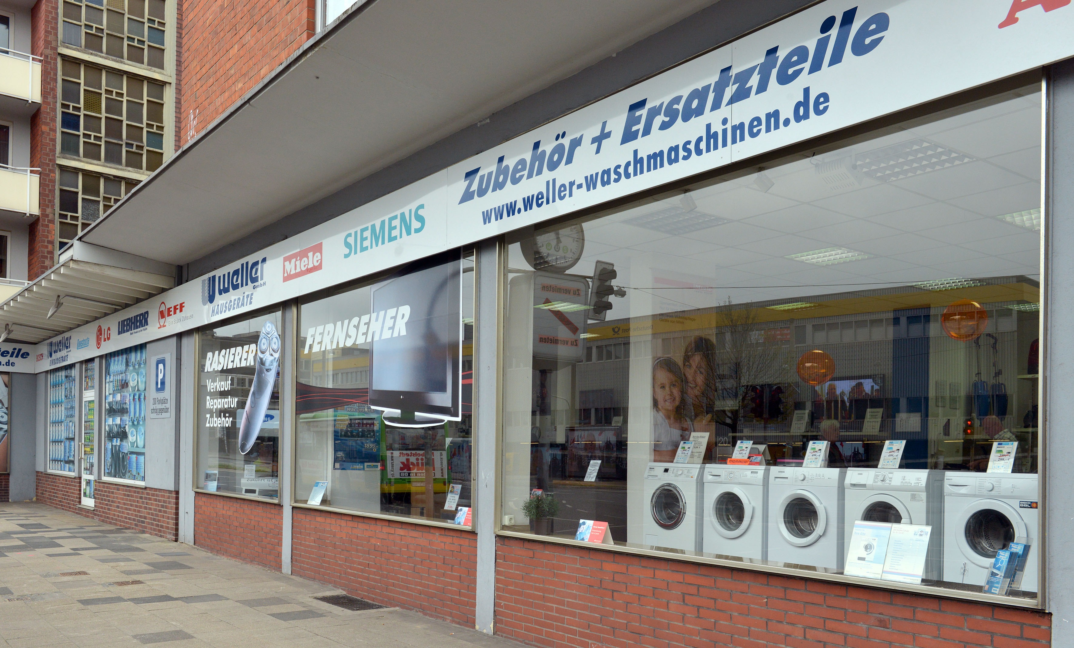 Elektrofachgeschäft mit Waschtrocknern und Haushaltsgeräten im Schaufenster.