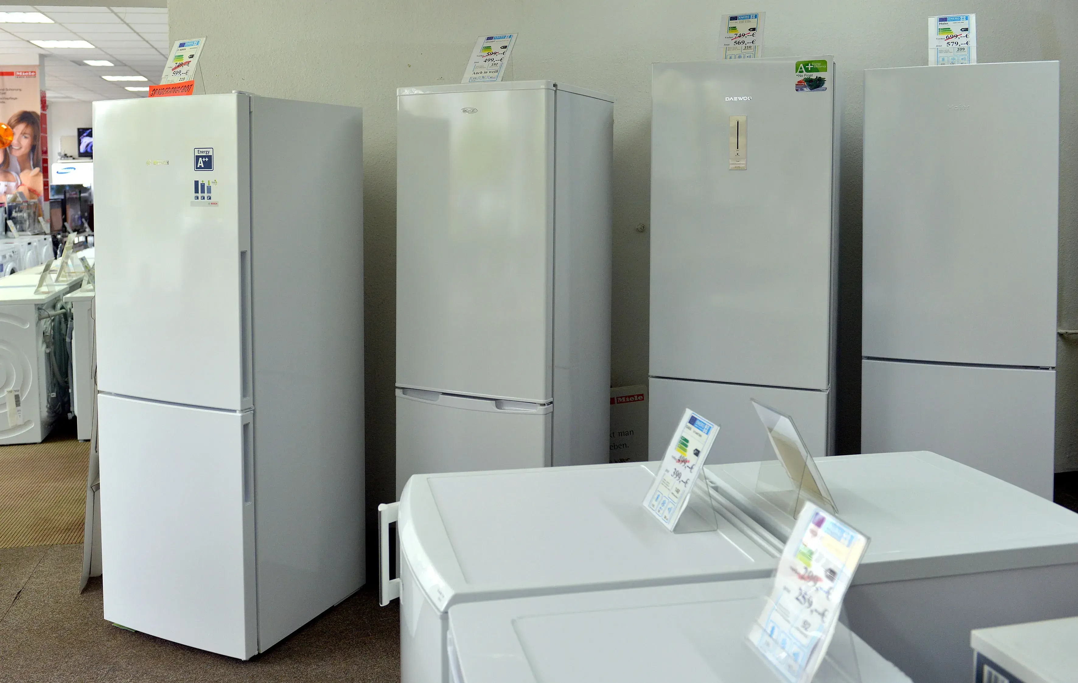 Mehrere weiße Kühlschränke stehen in einer Ausstellung im Elektrofachgeschäft.